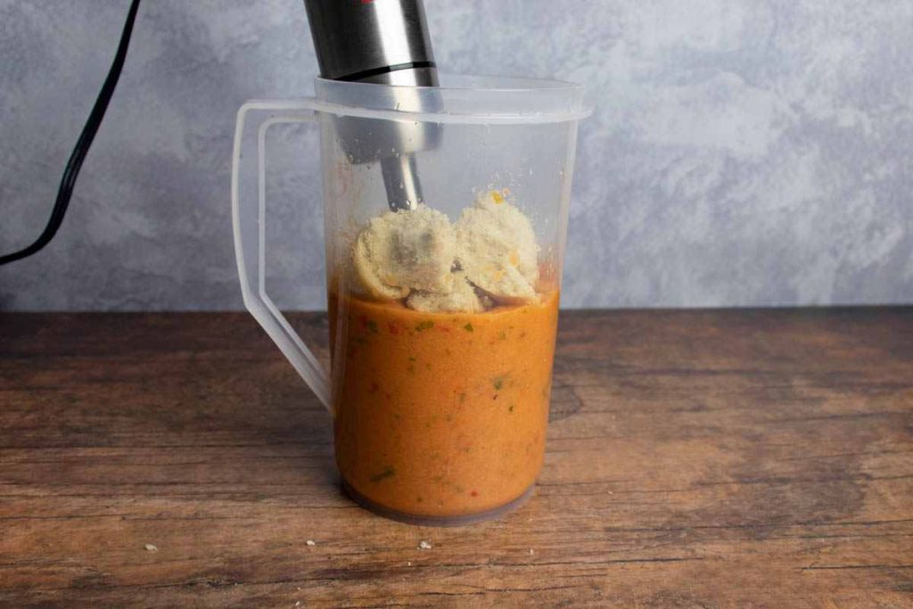 pitcher of gazpacho with bread and hand mixer